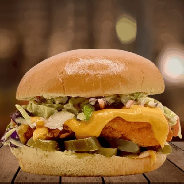 Five Star Chicken's fried chicken burger with melted cheese, lettuce, and pickles on a bun.